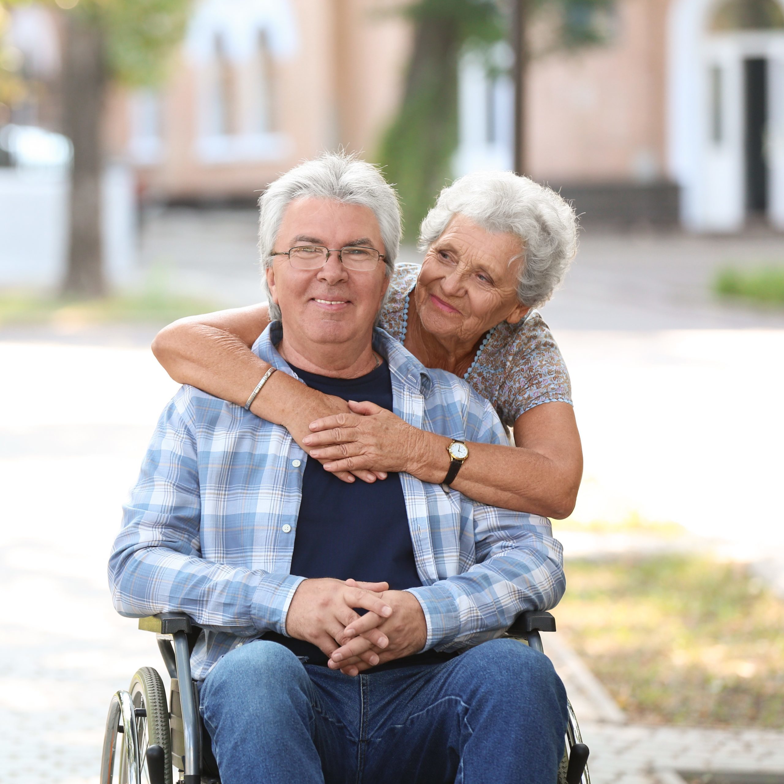 Happy senior man in wheelchair and his wife outdoors